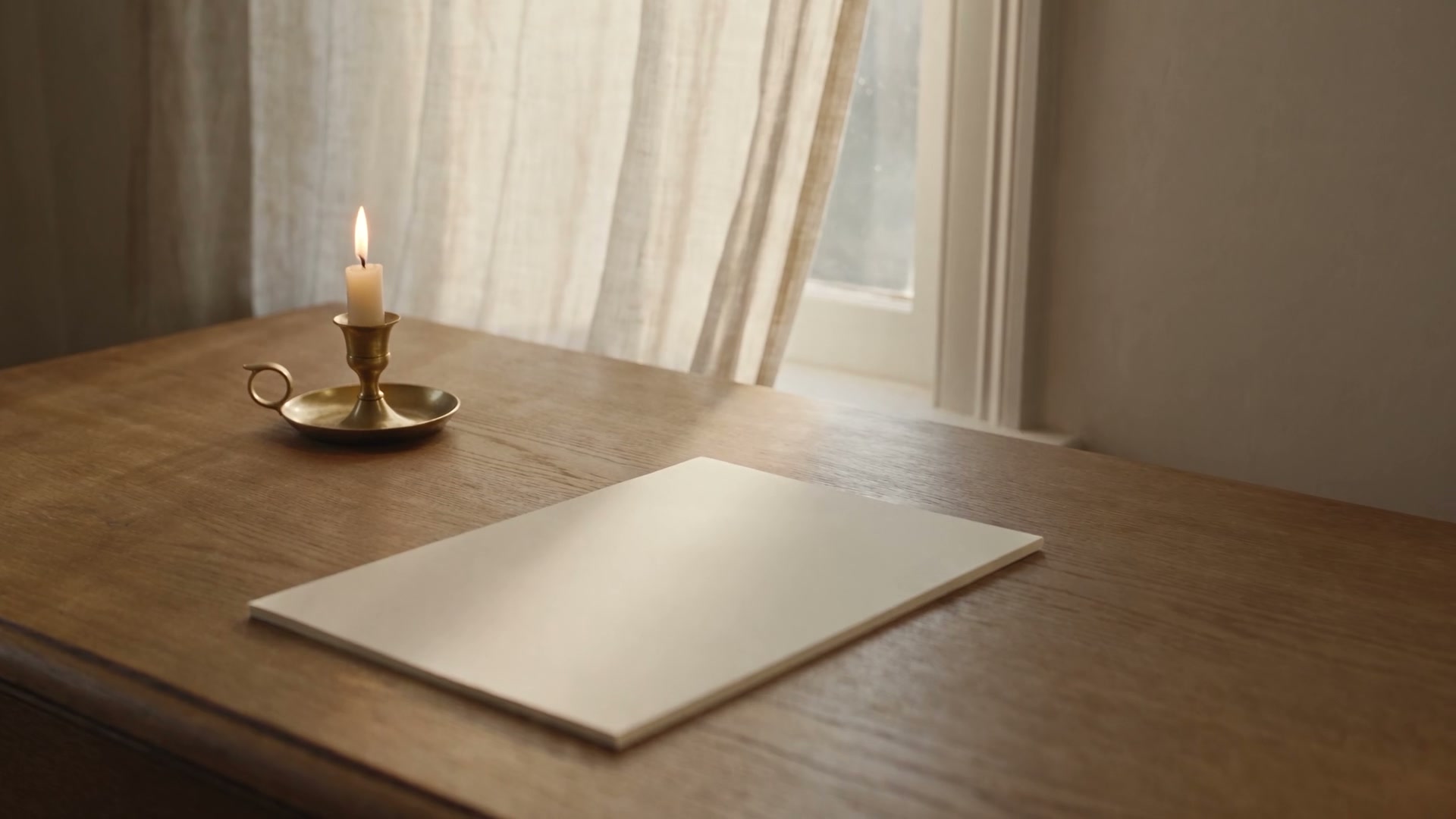 A blank cream sheet and a small brass candle on an oak desk in morning light